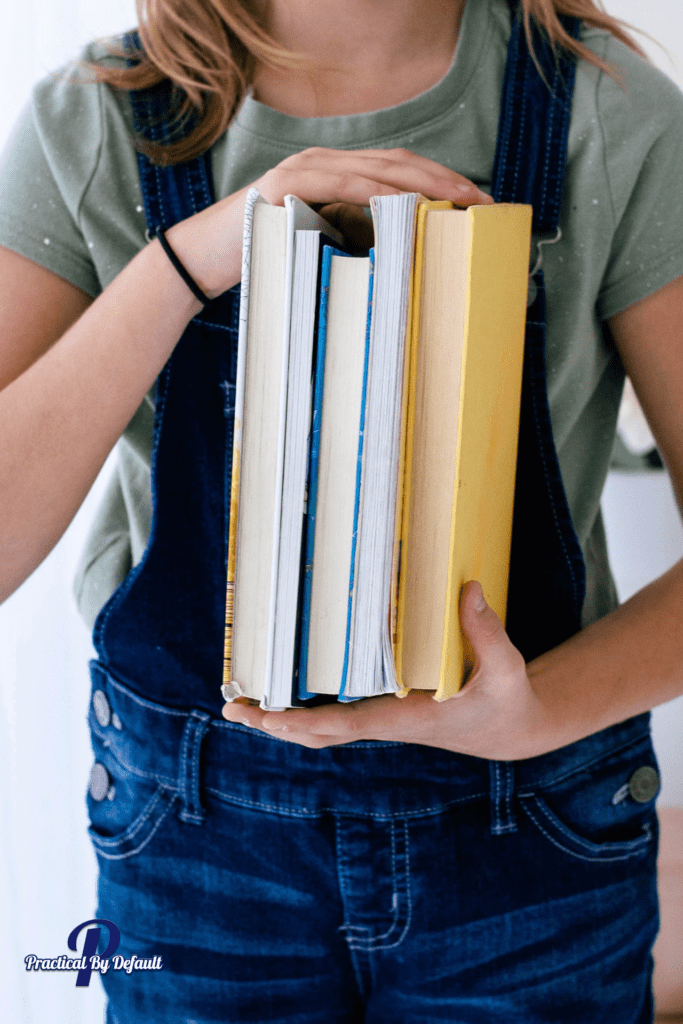 Child holding a stack of books getting organized for back to homeschool 